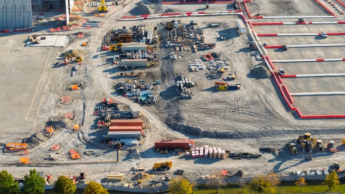 aerial view of large industrial construction site with trucks, shipping containers and equipment onsite