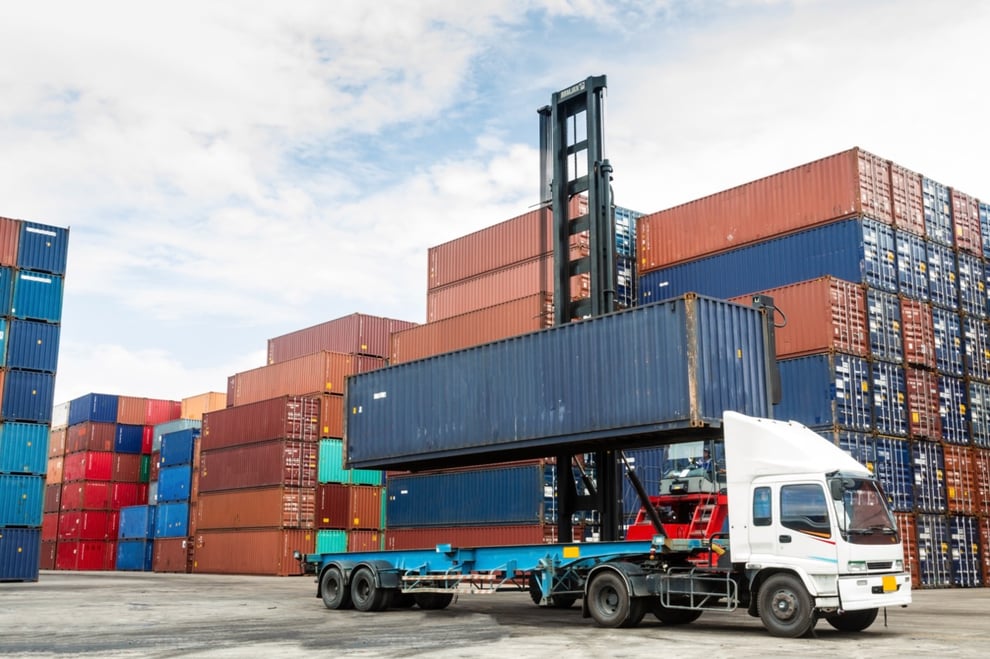 shipping container being lifted up by a crane for delivery