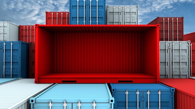 Empty red shipping container with open side stacked on top of blue containers