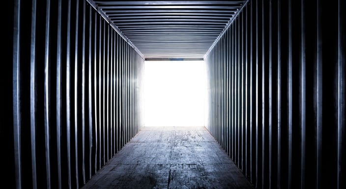inside long narrow empty shipping container with light at the open end