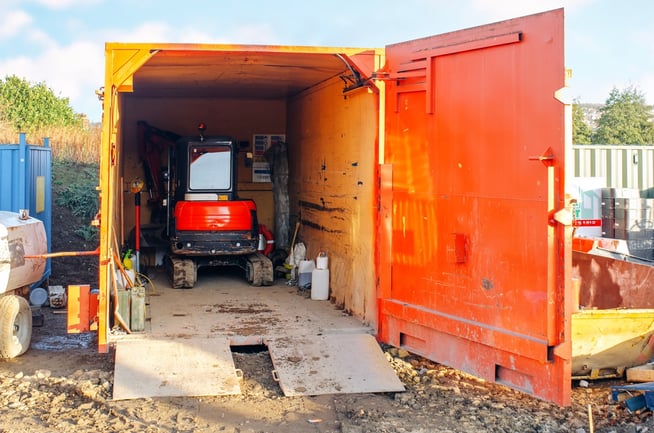 image of a bright orange shipping container on a construction job site storing tools and equipment
