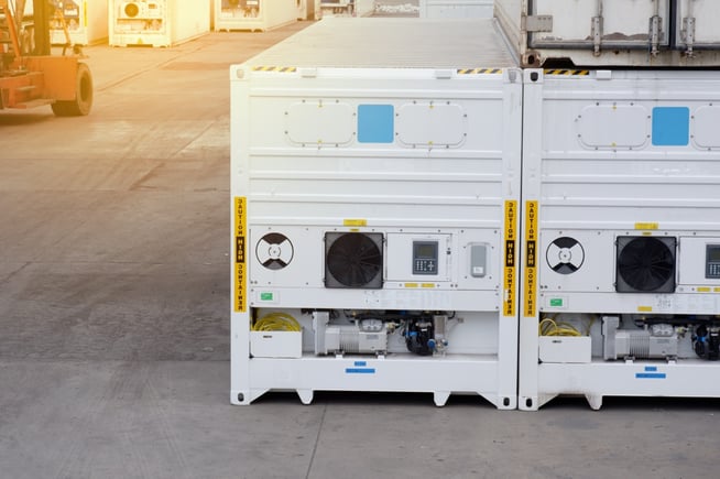 multiple white refrigerated containers with sunset in the background