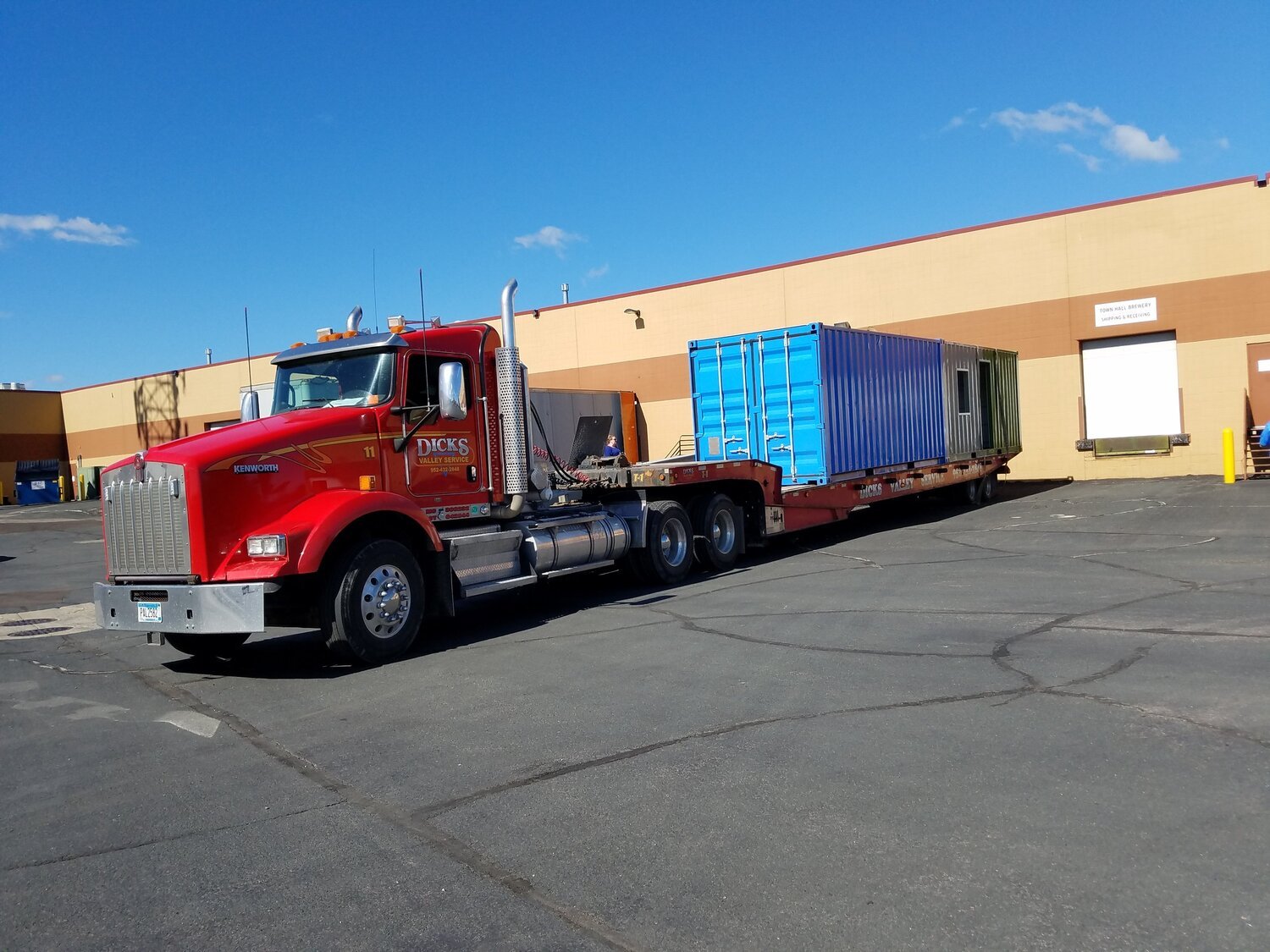 a blue container being delivered on a flatbed
