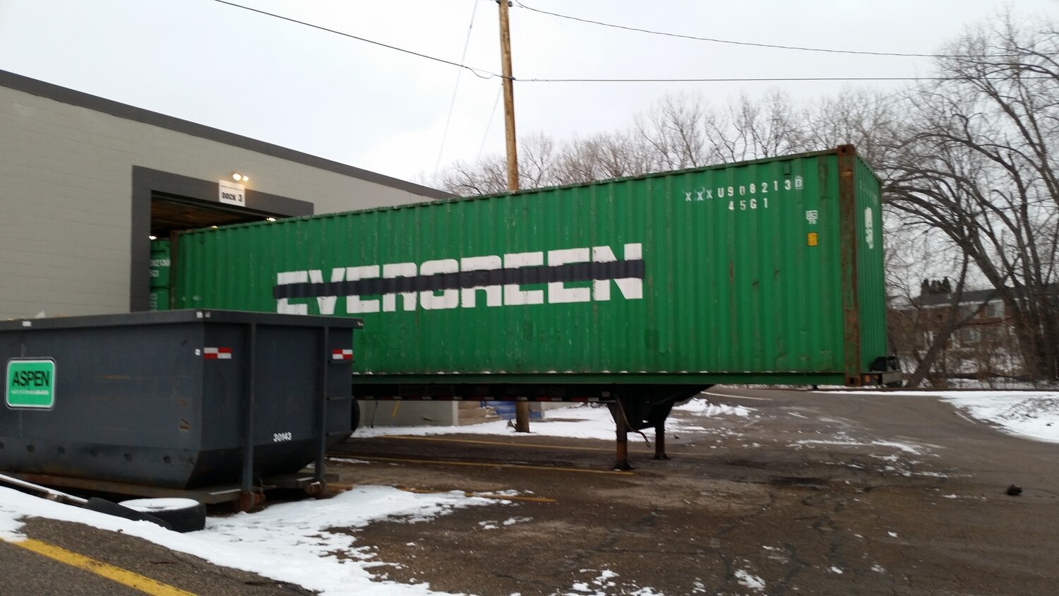a green shipping container used as extra storage from a building