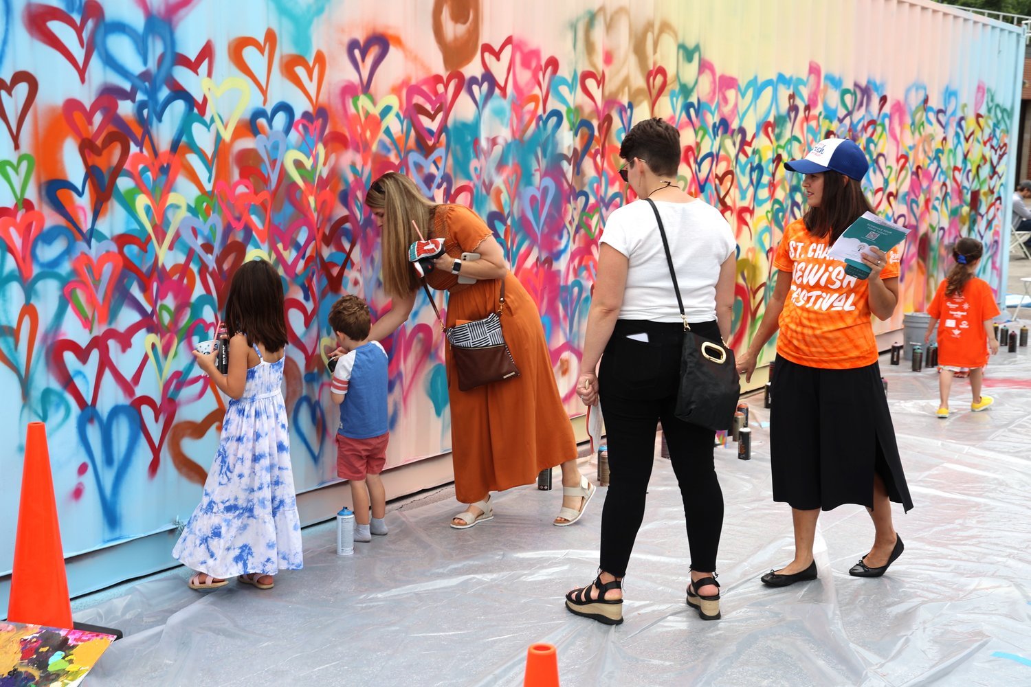 a bright container wall with children and adults drawing hearts on it
