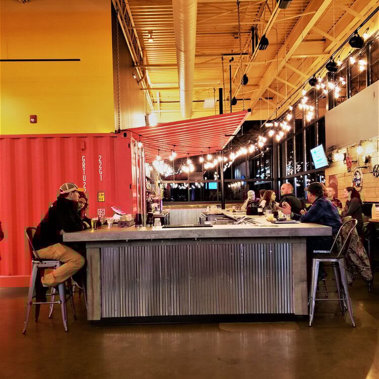 a shipping container bar with people sitting at the bar