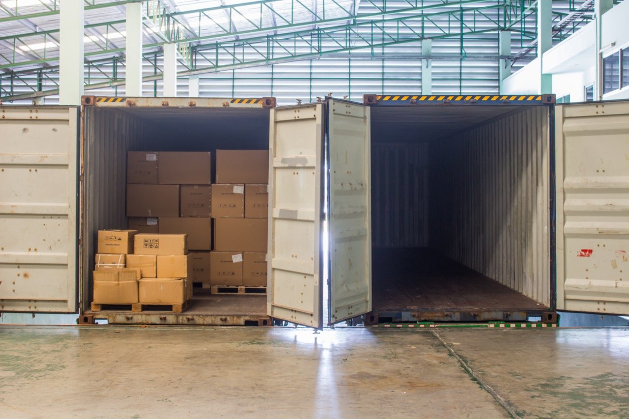 shipping containers with open doors insides warehouse building
