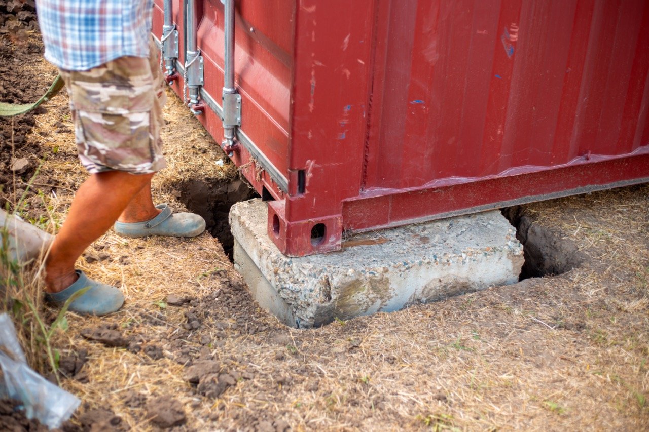 red shipping container placed on concrete blocking foundation