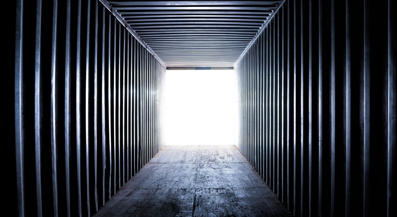inside long narrow empty shipping container with light at the open end