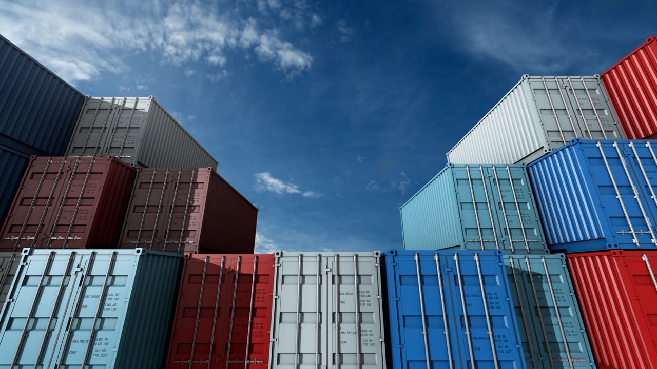 stacks of red, blue and white painted shipping containers in a container yard